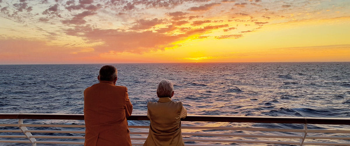 A couple admiring a sunset from the deck on Spirit of Adventure